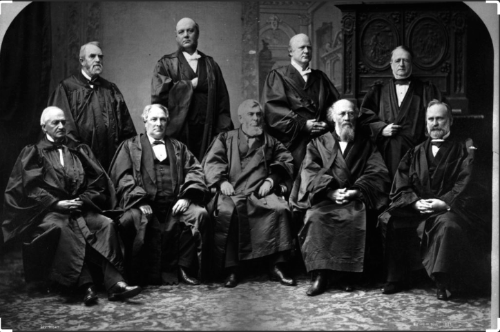 Black and white historical photograph of the Supreme Court justices seated and standing in formal attire, likely from the late 19th century.